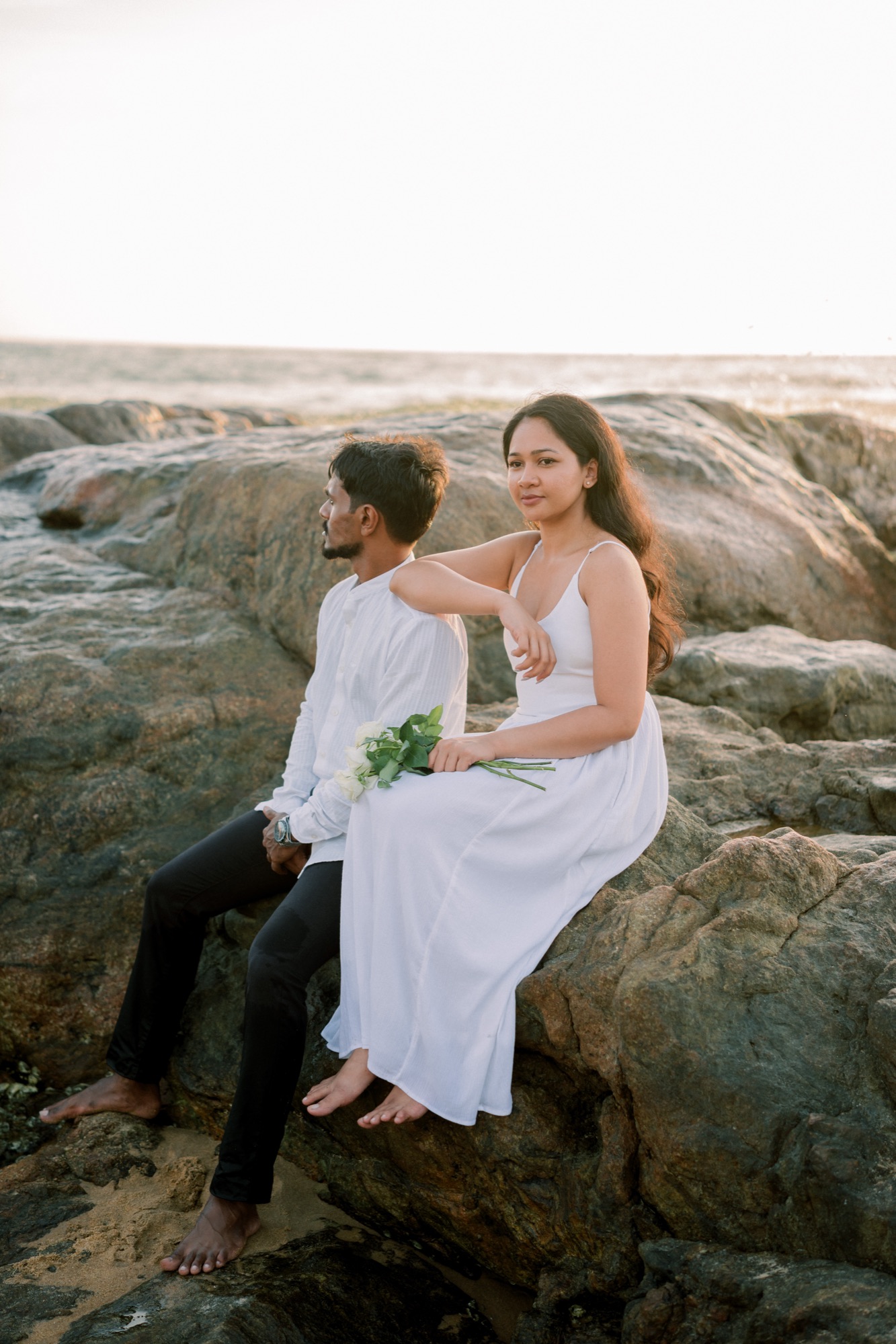 Wazeefa and Damiru sitting together on the rocks by the sea
