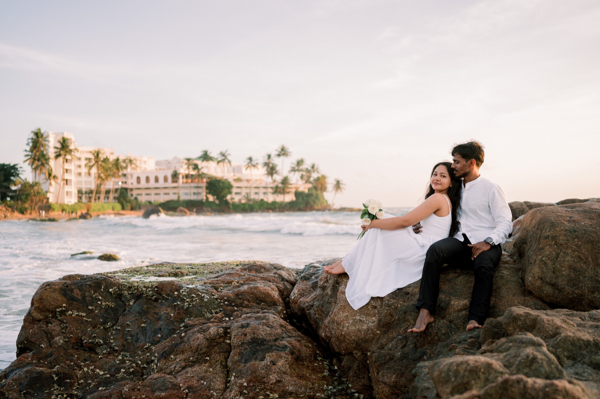 Wazeefa and Damiru sitting on the rocks with Galle Face Hotel in the background